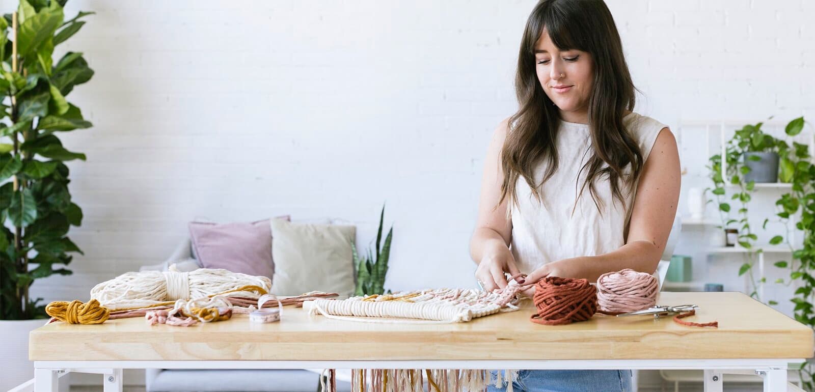 A maker knotting a macrame wall hanging at a workbench
